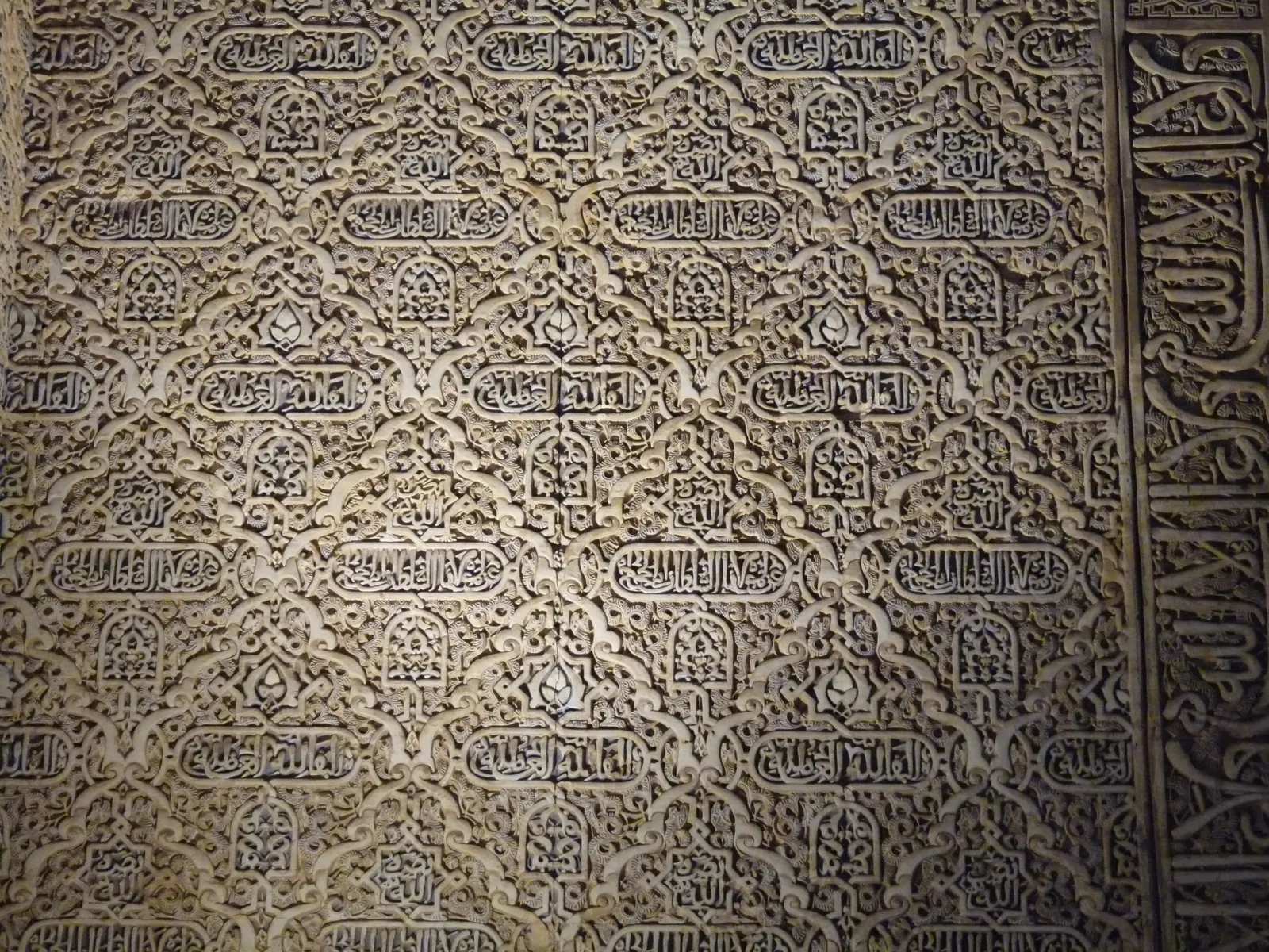 Tencuială sculptată: o rețea de romburi cu cartușe cu inscripții arabe.