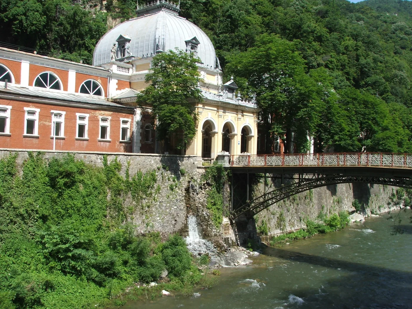 Băile imperiale Neptun văzute de peste Cerna, cu podul de fontă în prim-plan