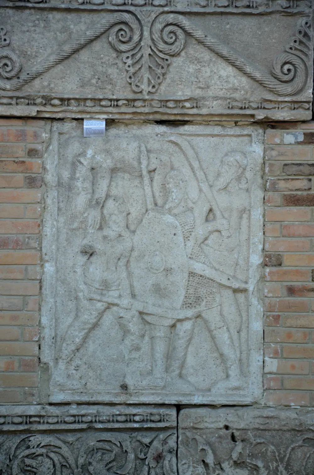Metopă de pe monumentul triumfal al lui Traian de la Adamclisi (Tropaeum Traiani), cu un soldat roman luptând cu daci bărboși.