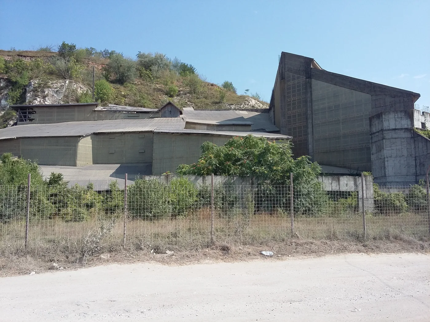 Construcția de beton care acoperă complexul rupestru, văzută de după gard
