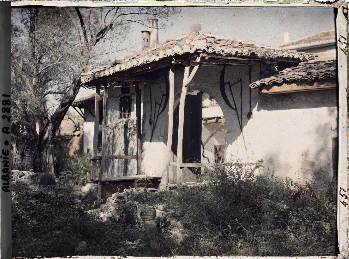 Fotografie color de epocă a unui loc de cult bektashi din Tirana, cu însemne desenate pe ziduri