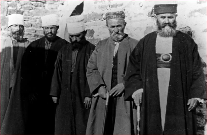 Cinci derviși bătrâni în haine lungi și acoperăminte de cap, la tekke-ul bektashi din Përmet