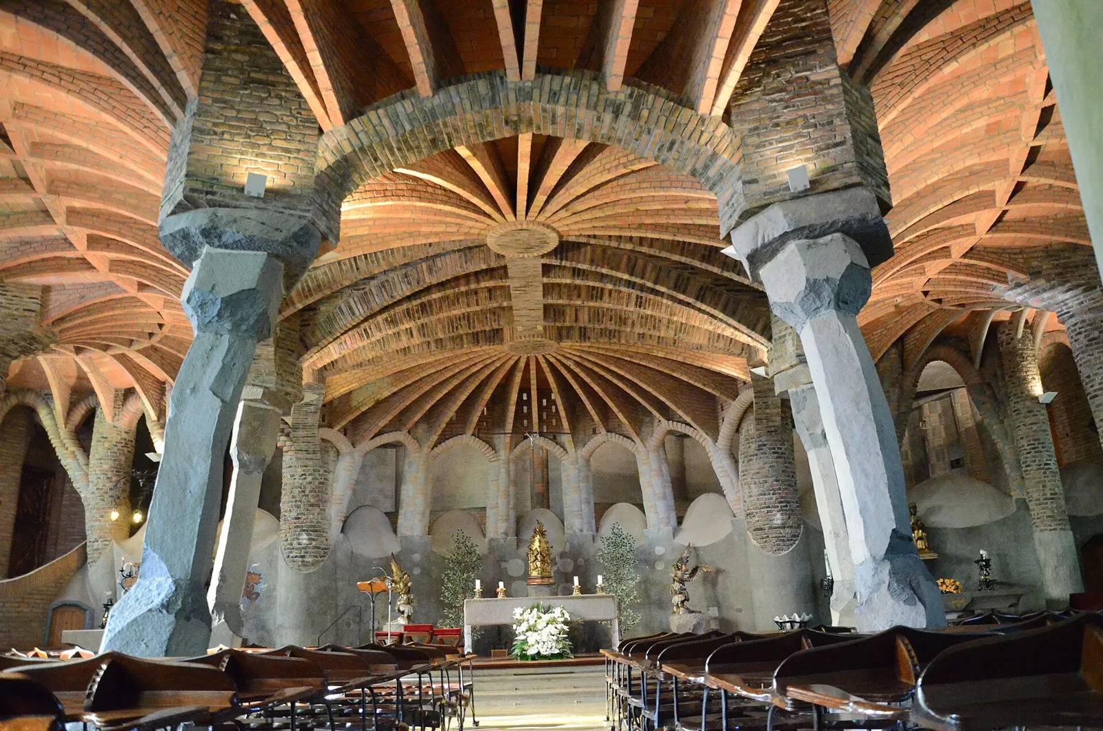Inside the Colònia Güell crypt: leaning stone columns under brick vaults
