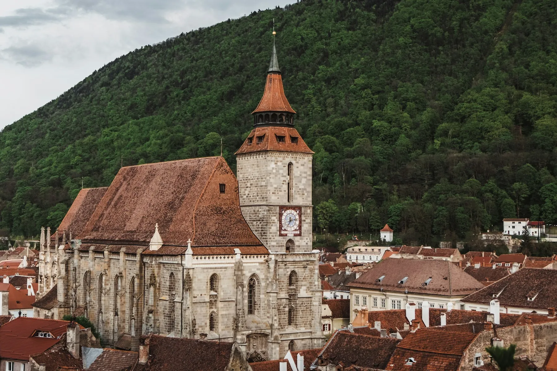 The Black Church with its steep roof and clock tower, beneath the wooded hill