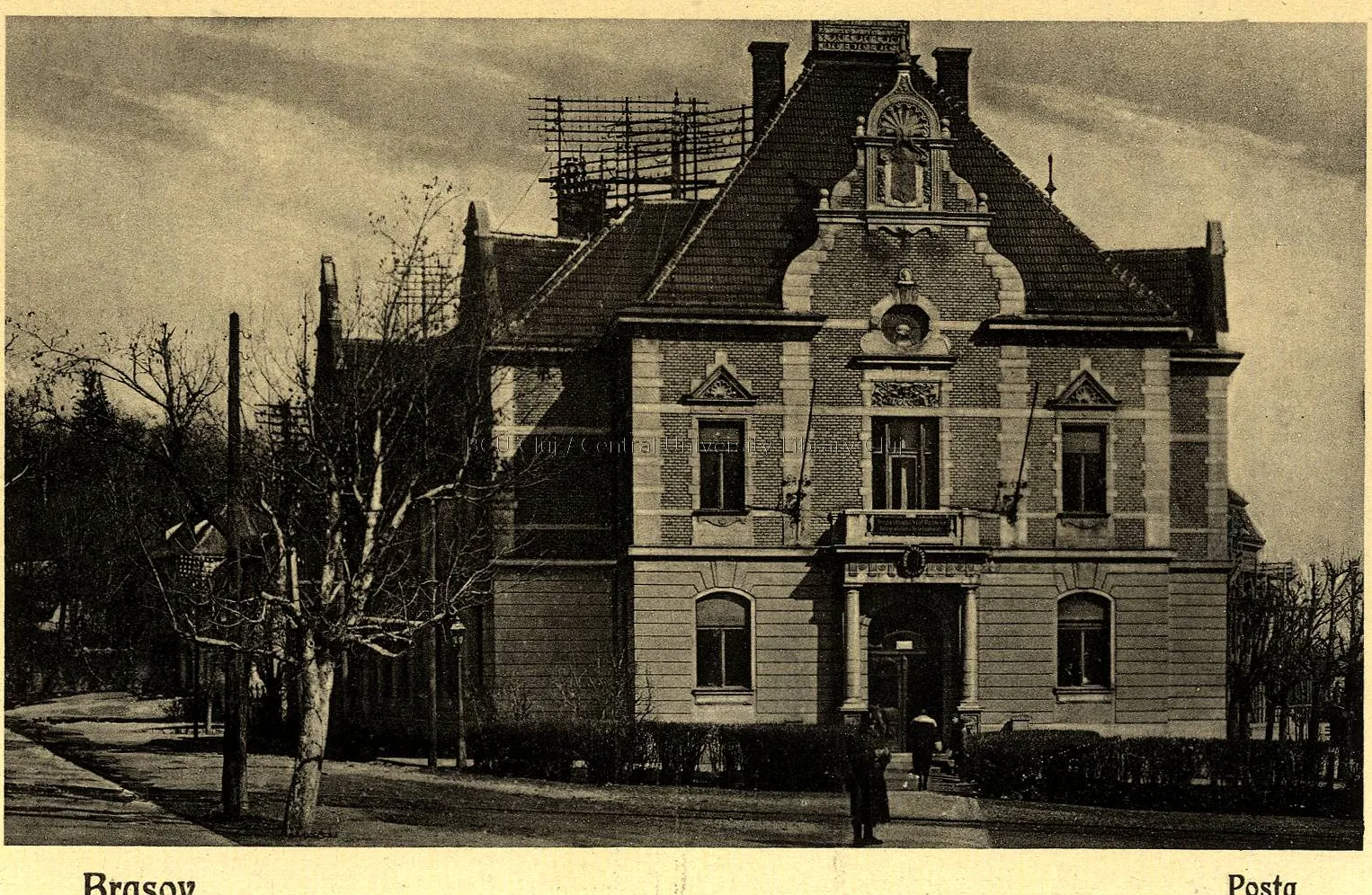 Fotografie alb-negru: clădirea poștei, cu turnuleț, printre copaci desfrunziți