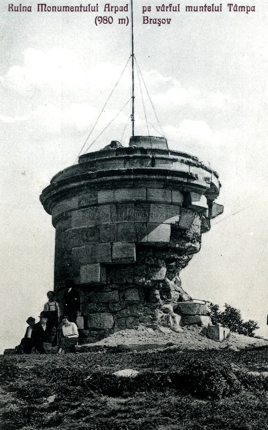 Carte poștală alb-negru: soclul rotund și spart al monumentului, cu un catarg în vârf