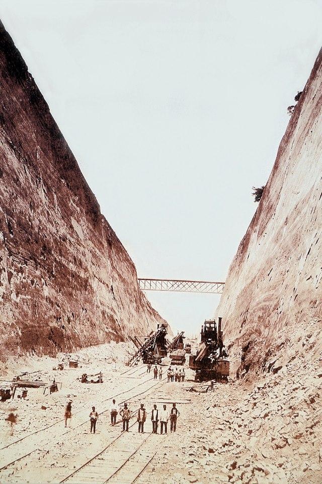 Fotografie colorată manual din șantier: tăietură adâncă, muncitori, excavatoare cu abur, șine și un pod.