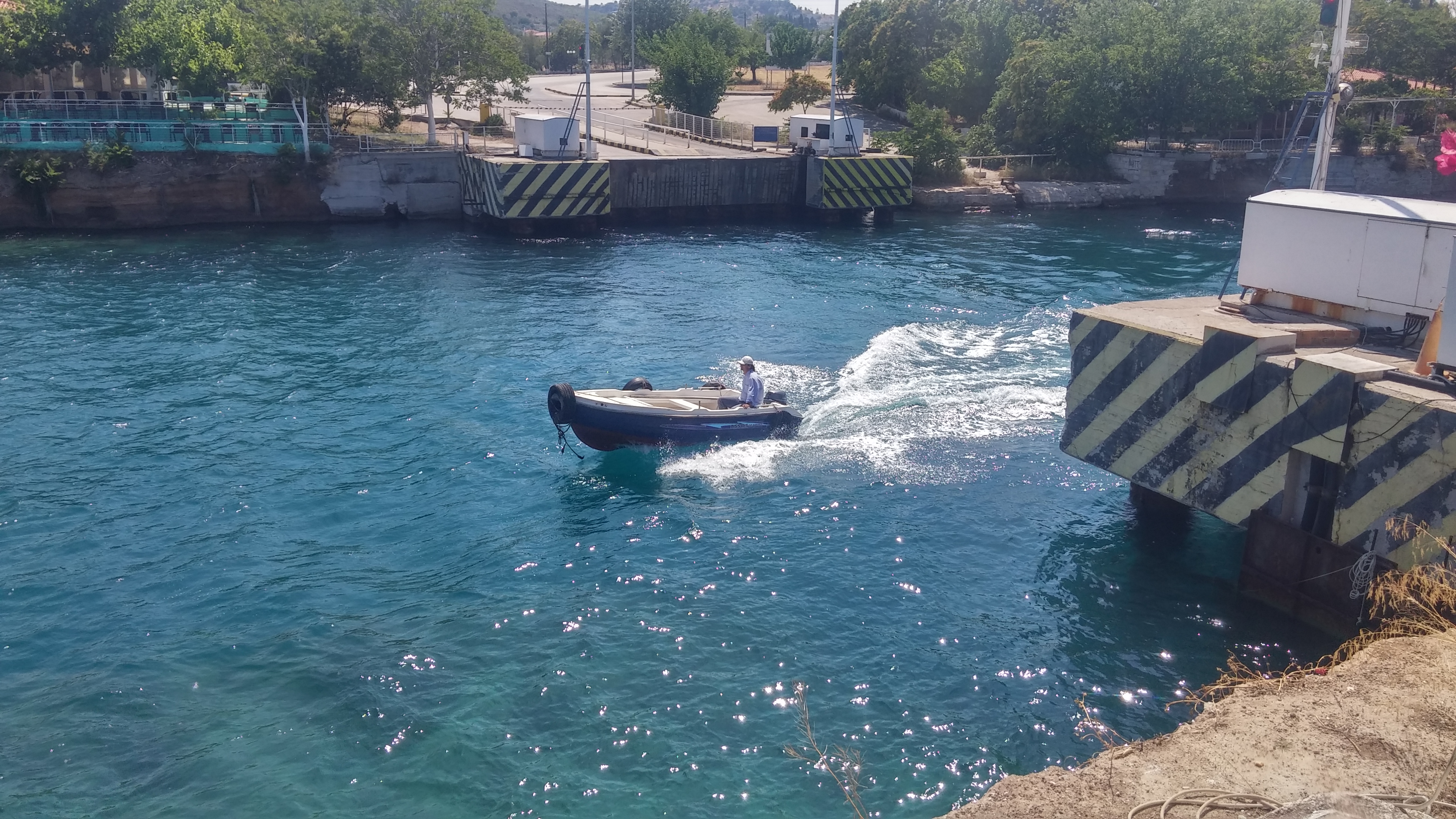 La Isthmia, podul submersibil este coborât sub apă, iar o barcă trece deasupra lui.