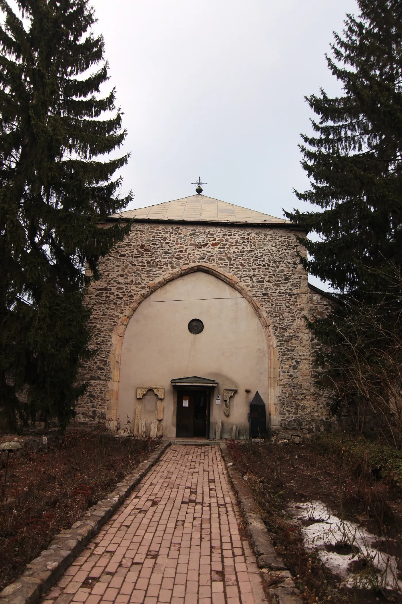 Fațada gotică a Bărăției din Câmpulung, cu un portal în arc frânt, între doi brazi înalți.