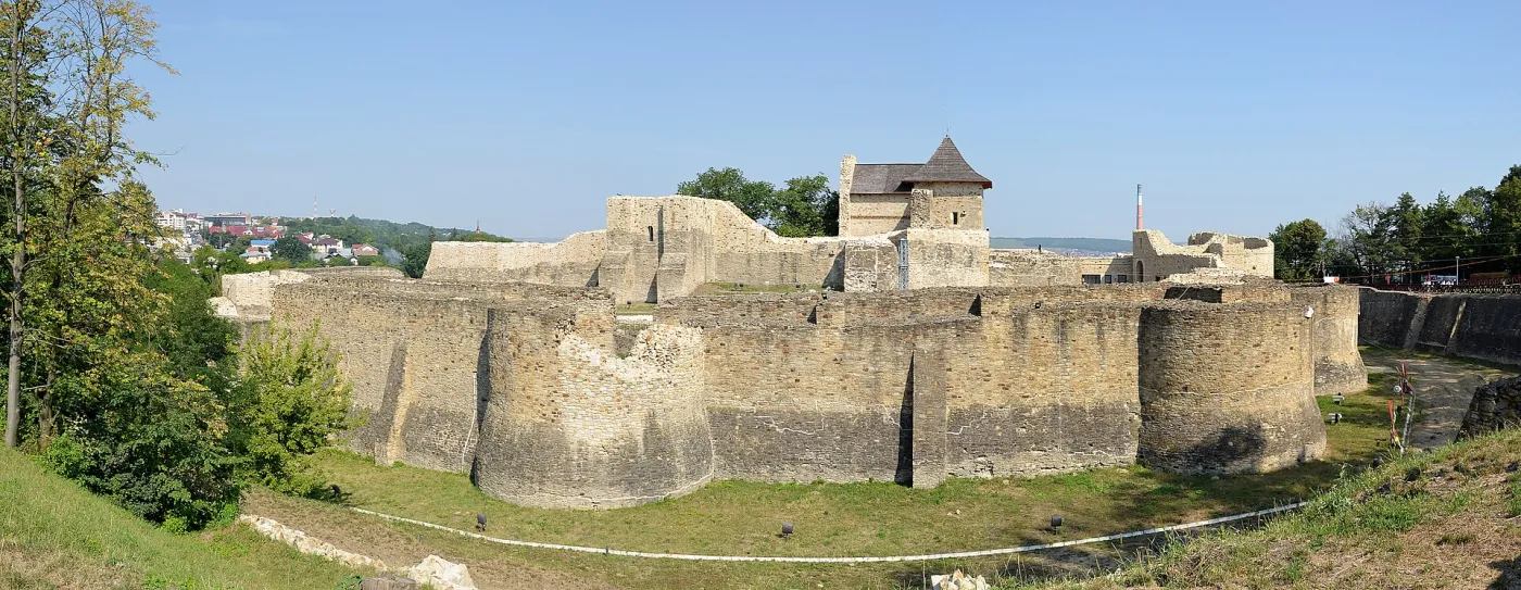 Zidurile de piatră ale Cetății de Scaun a Sucevei, cu turnuri și șanț, sub un cer senin.