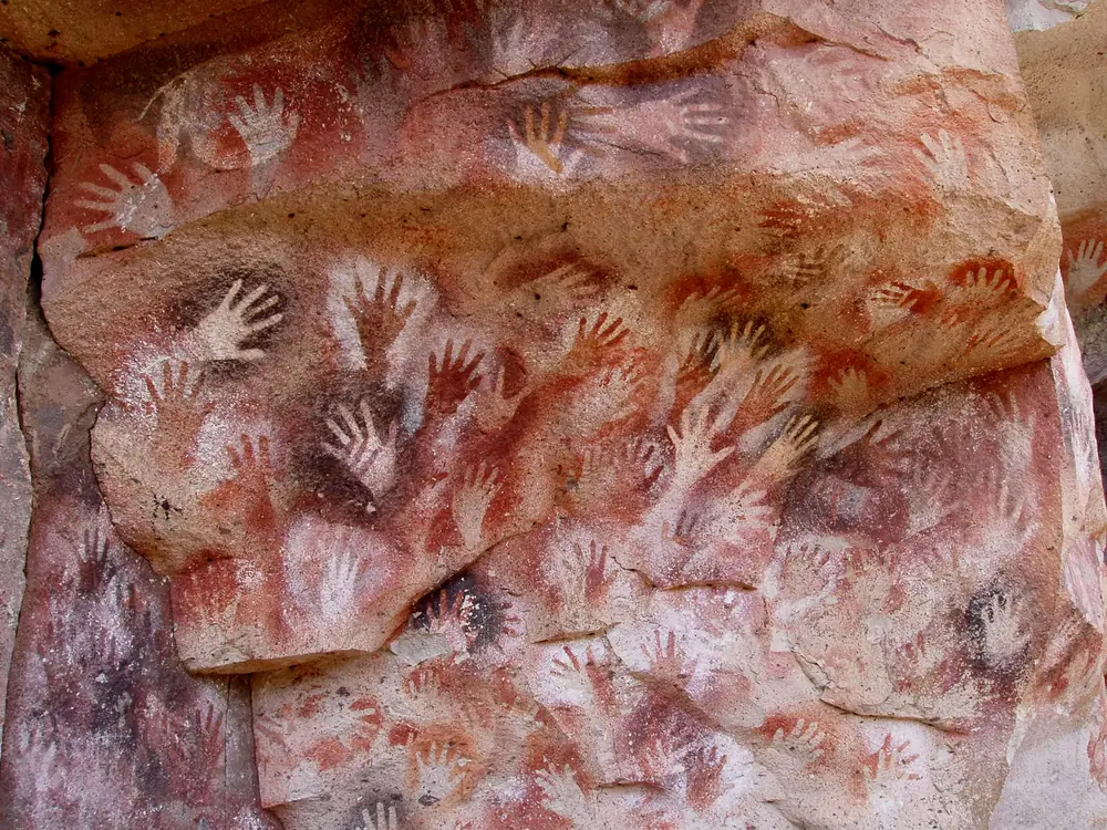 A red and white wall covered with hand stencils at Cueva de las Manos