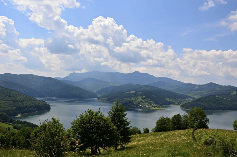 Lacul Bicaz între munți împăduriți, cu masivul Ceahlău în zare.