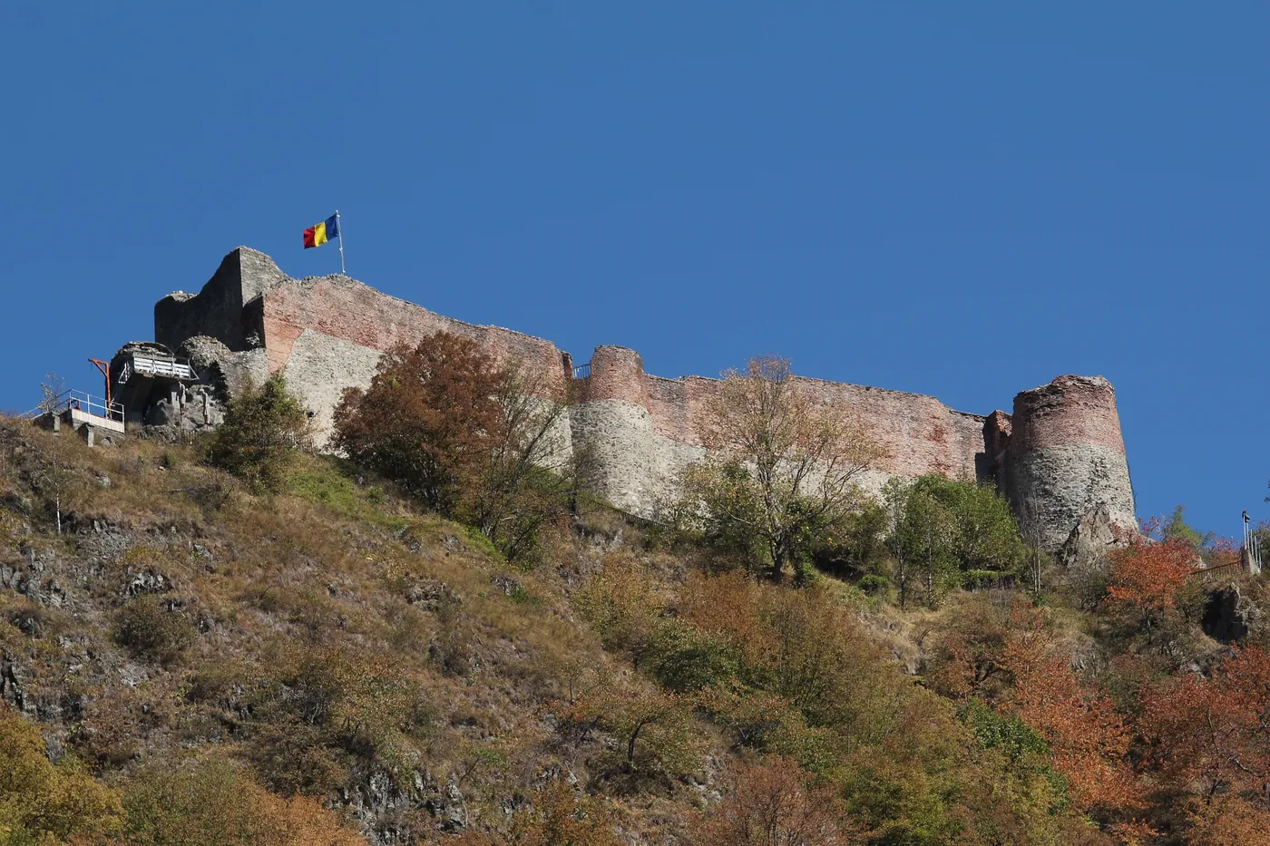 Poenari Fortress on the ridge, with the Romanian flag.