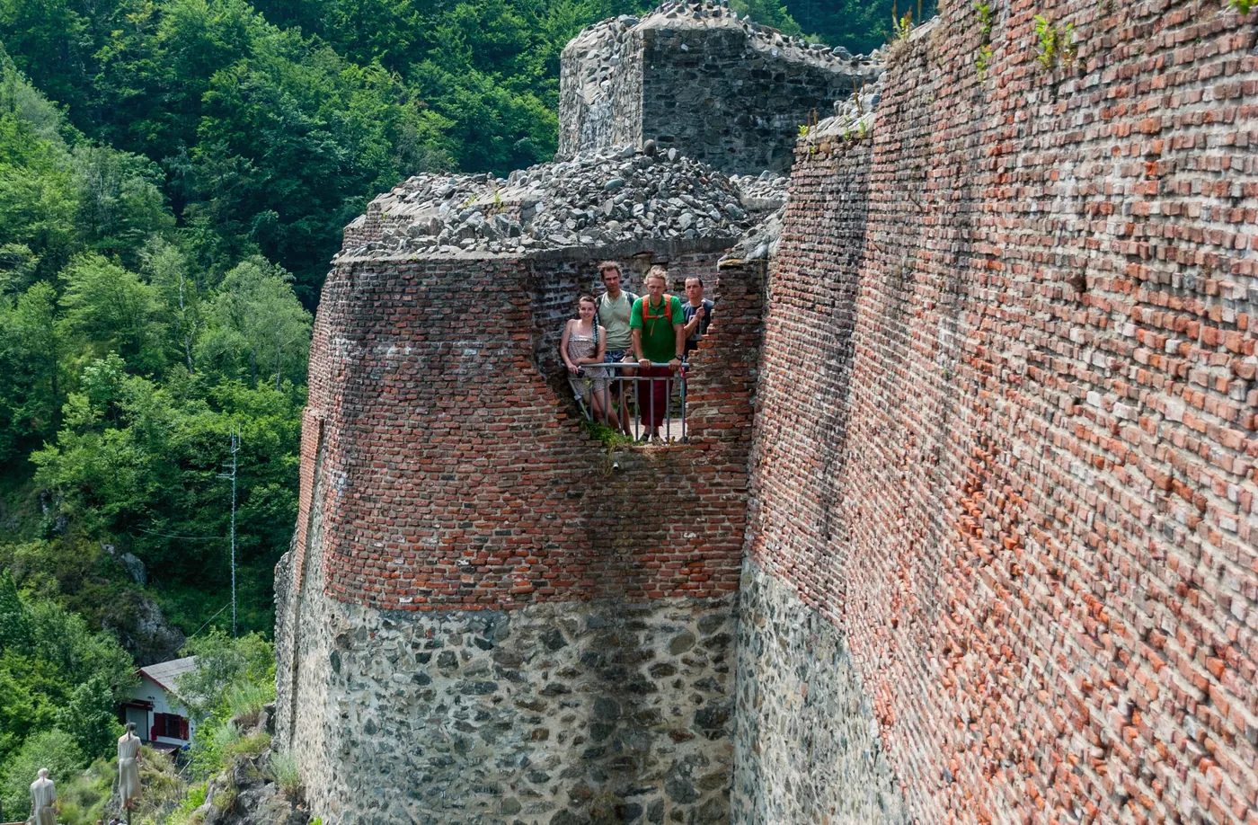 The brick tower of Poenari Fortress, with tourists on the upper platform.