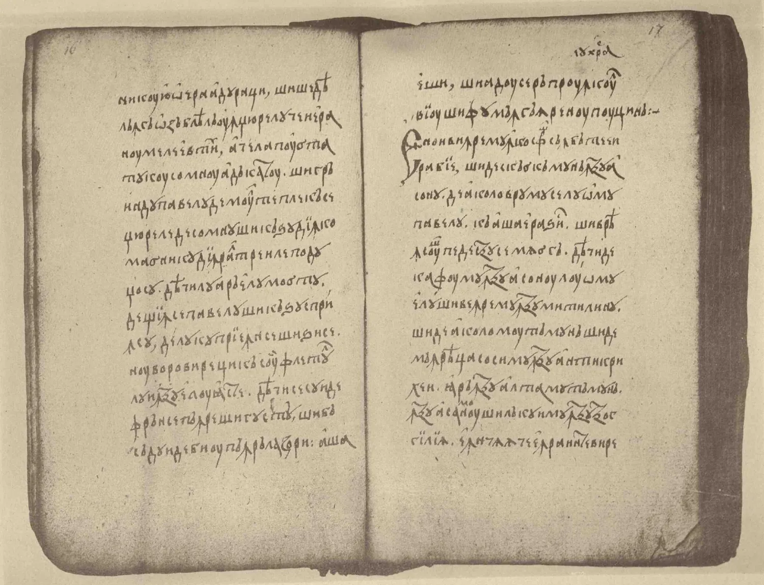 An old photograph of a manuscript lying open: two pages handwritten in Cyrillic letters, fourteen lines to a page.