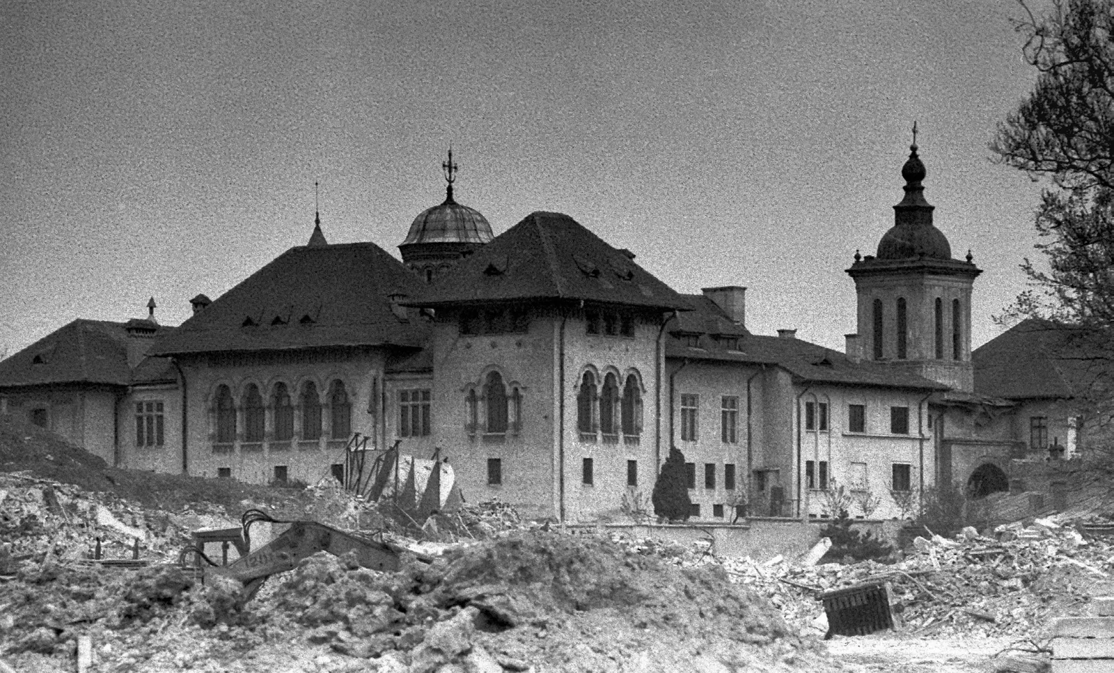The church and belfry of Mihai Vodă standing among rubble in 1986, an excavator at work