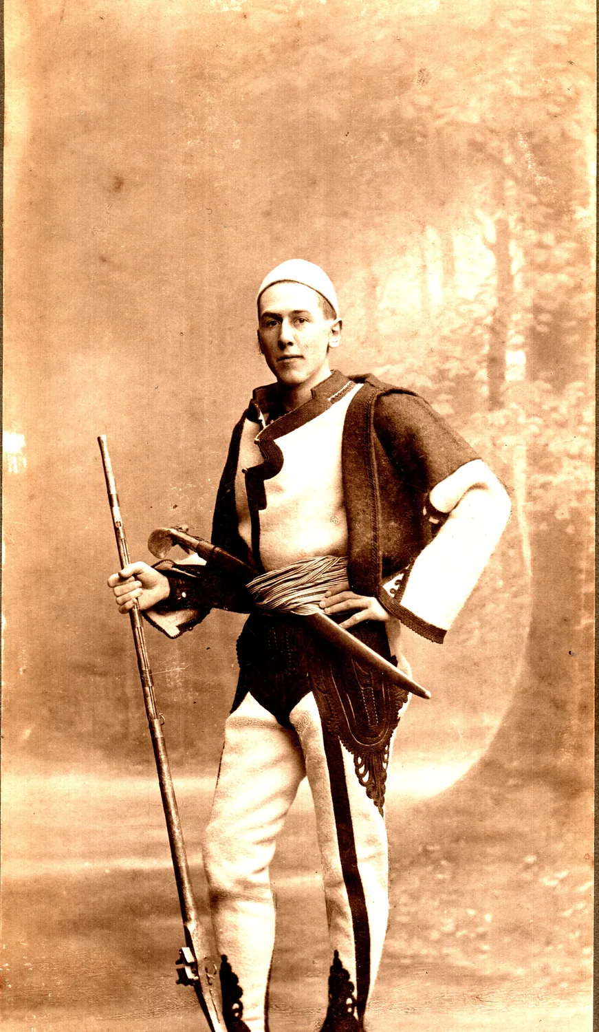 Fotografie veche de studio: Franz Nopcsa în costum de luptător albanez, cu pușcă.