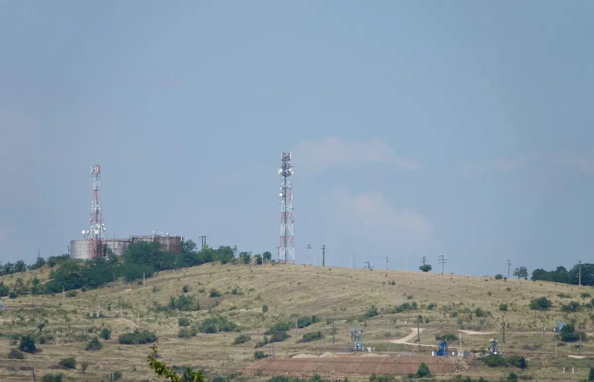 Pompă mecanică de extracție a țițeiului funcționând într-o livadă din Țintea-Băicoi