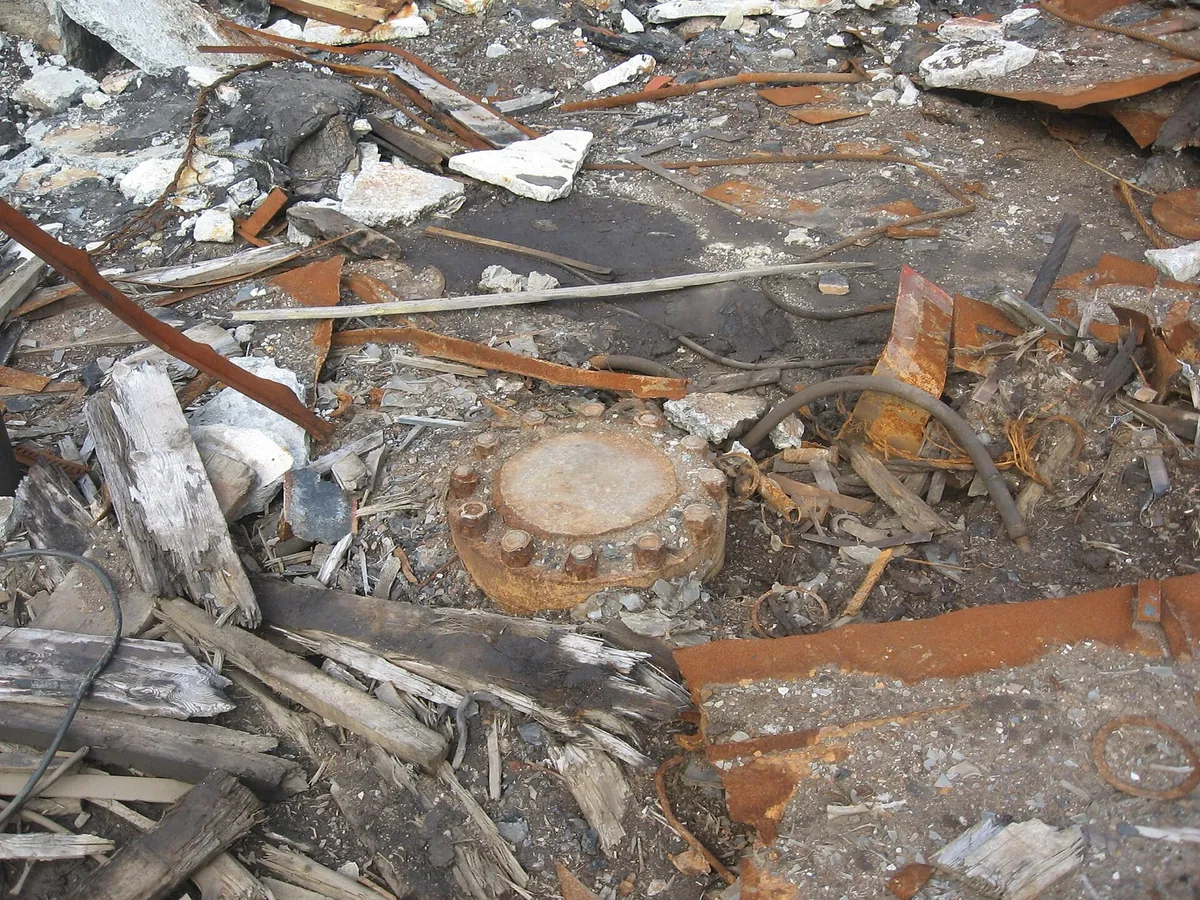 A rusted metal cap welded over the Kola borehole, among concrete ruins