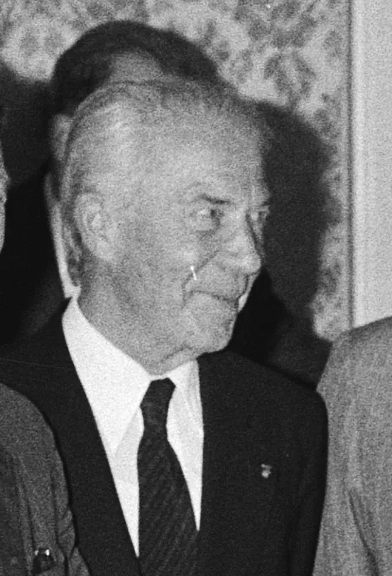 Fotografie alb-negru a unui bărbat cu părul alb, în costum.