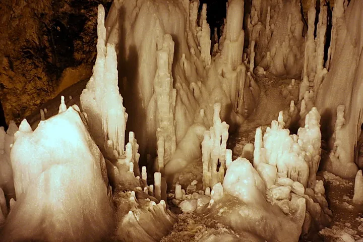Tall thin white ice stalagmites rising from the floor of the Church hall under warm light