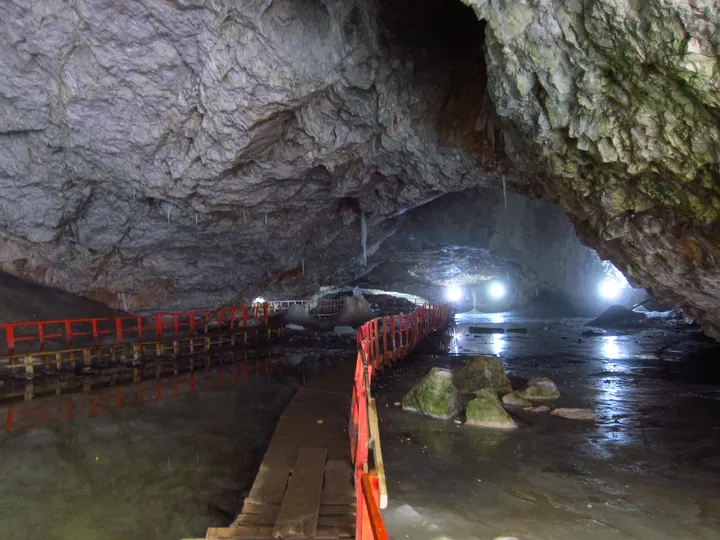 A wooden walkway over summer meltwater in the ice hall, with wet stone walls all around
