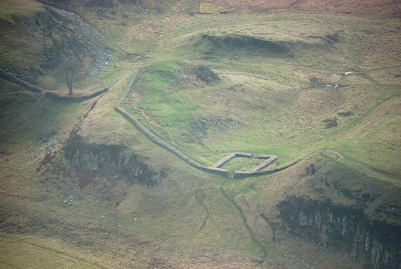 Aerial view of Sycamore Gap and the ruins of milecastle 39, with the Wall climbing the ridge.