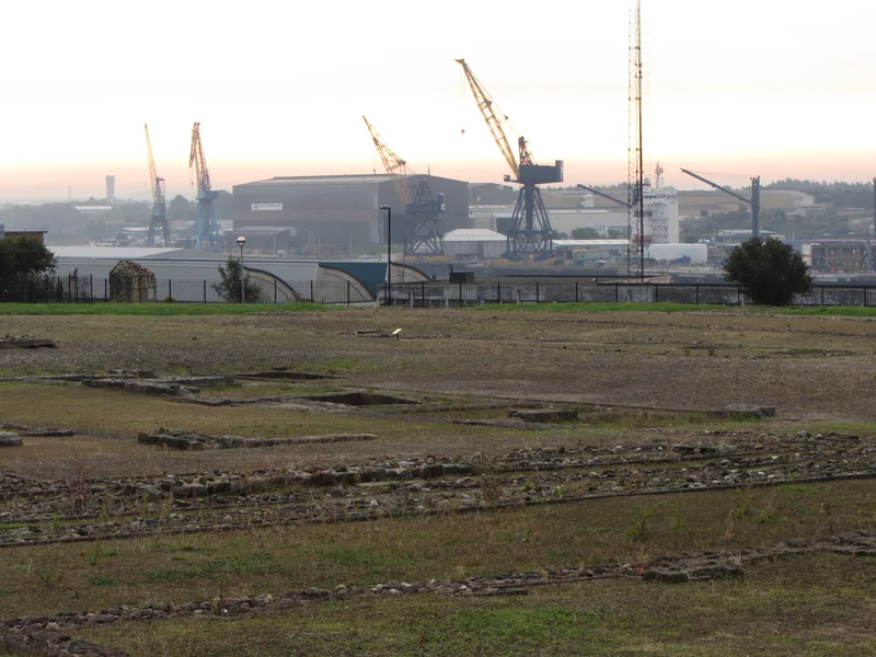 The foundations of Segedunum fort at Wallsend, with shipyard cranes behind.