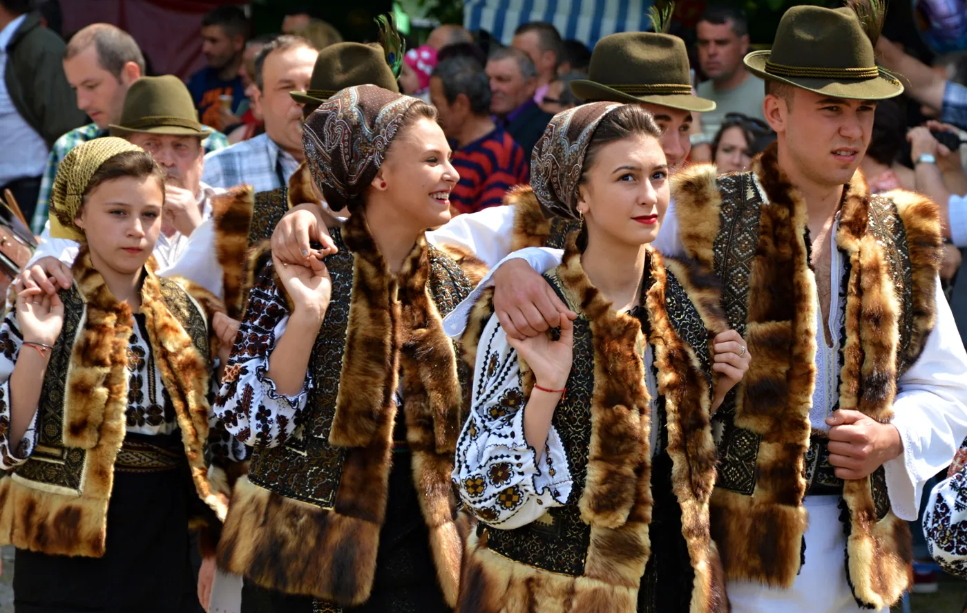 Young people in folk dress dancing the hora, arms on shoulders