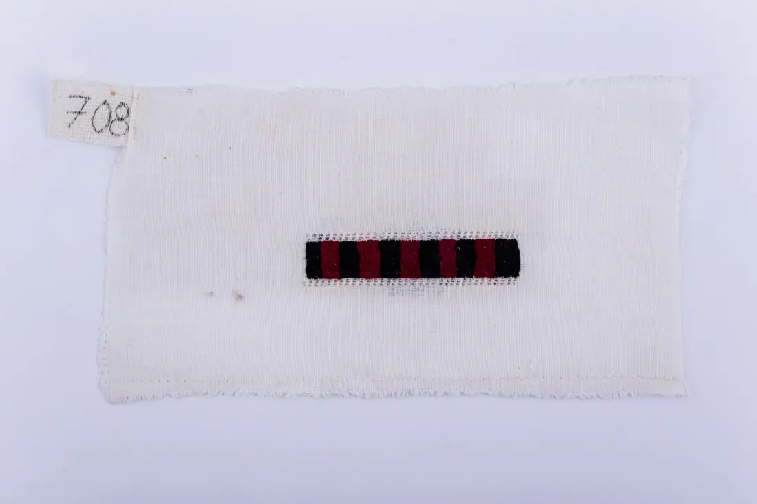 Fotografia muzeului: un model de broderie pe pânză albă, cu fir negru, roșu, cusut de Soră Mitrea Ciutană