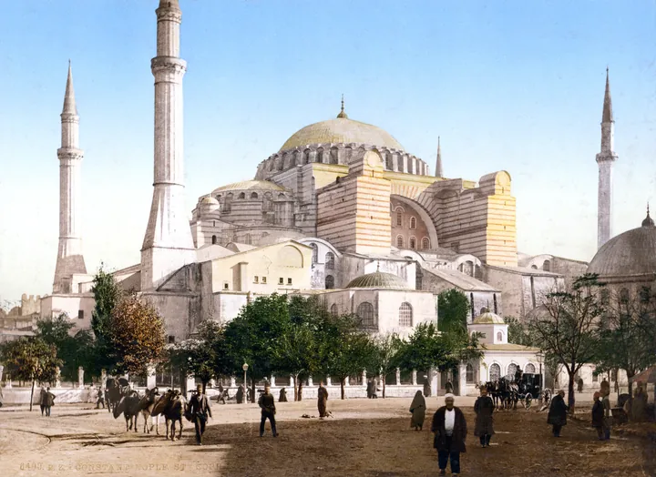 Hagia Sophia seen across a square, its great dome ringed by four minarets, in a tinted period photograph.