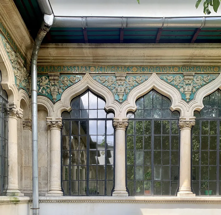 Prim-plan cu discuri de ceramică smălțuită, albastră și ocru, și brâuri sculptate pe zidăria albă