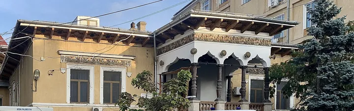 Casa Lahovari azi, văzută de aproape: foișorul alb cu stâlpi sculptați și friza cu ghirlande, sub streașină