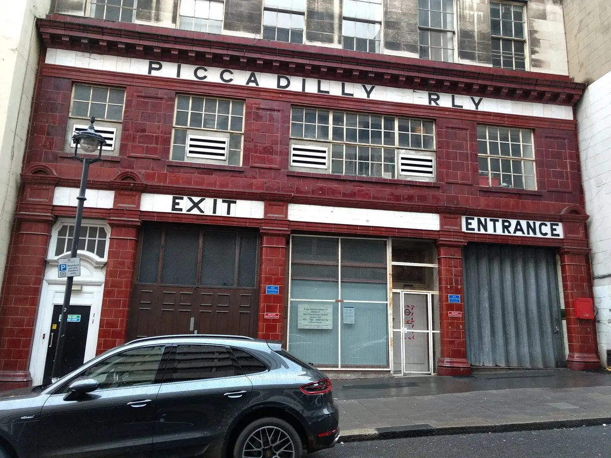 Red-tiled station front on Surrey Street with the words Piccadilly Rly, Exit and Entrance.