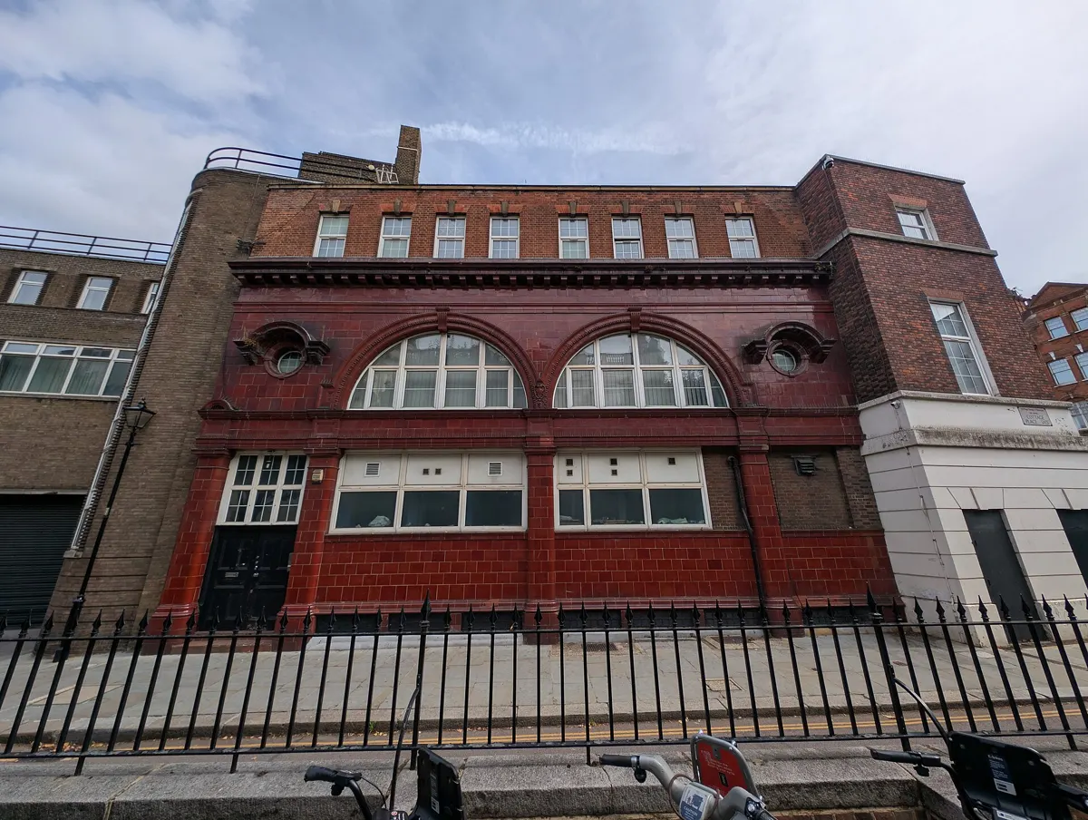 Brompton Road station building behind railings, with arched first-floor windows.