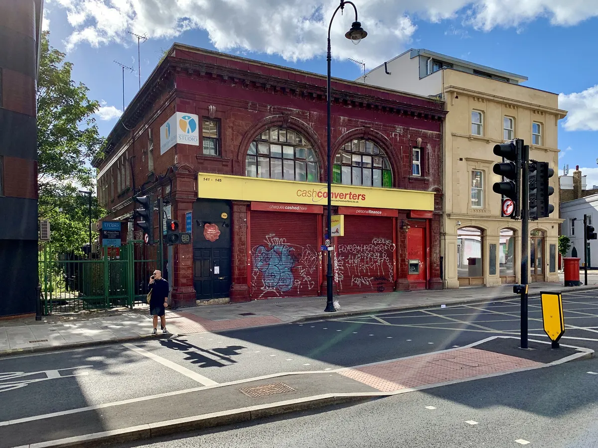 Corner building with red tiles and arched windows, now a shop, on Kentish Town Road.