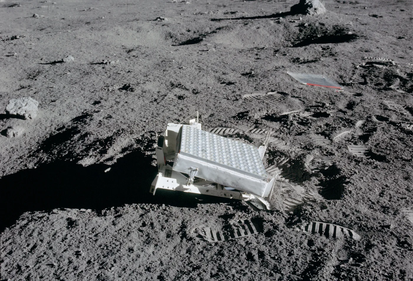 A flat panel of hundreds of small squares standing on grey lunar soil, with footprints around it