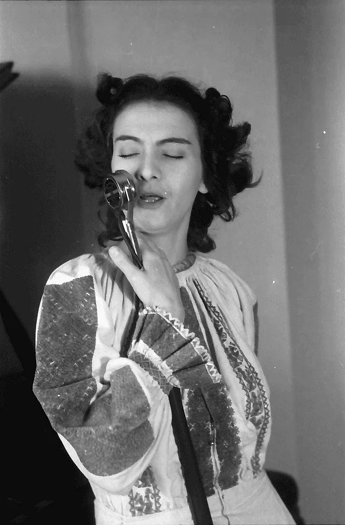 Maria Tănase cântând la microfon în apartamentul ei, martie 1942, fotografie de Willy Pragher