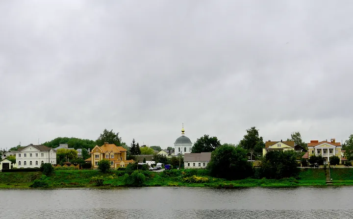 Fluviul Volga lat și liniștit la Tver, cu maluri verzi și un pod în depărtare, sub cer de vară.