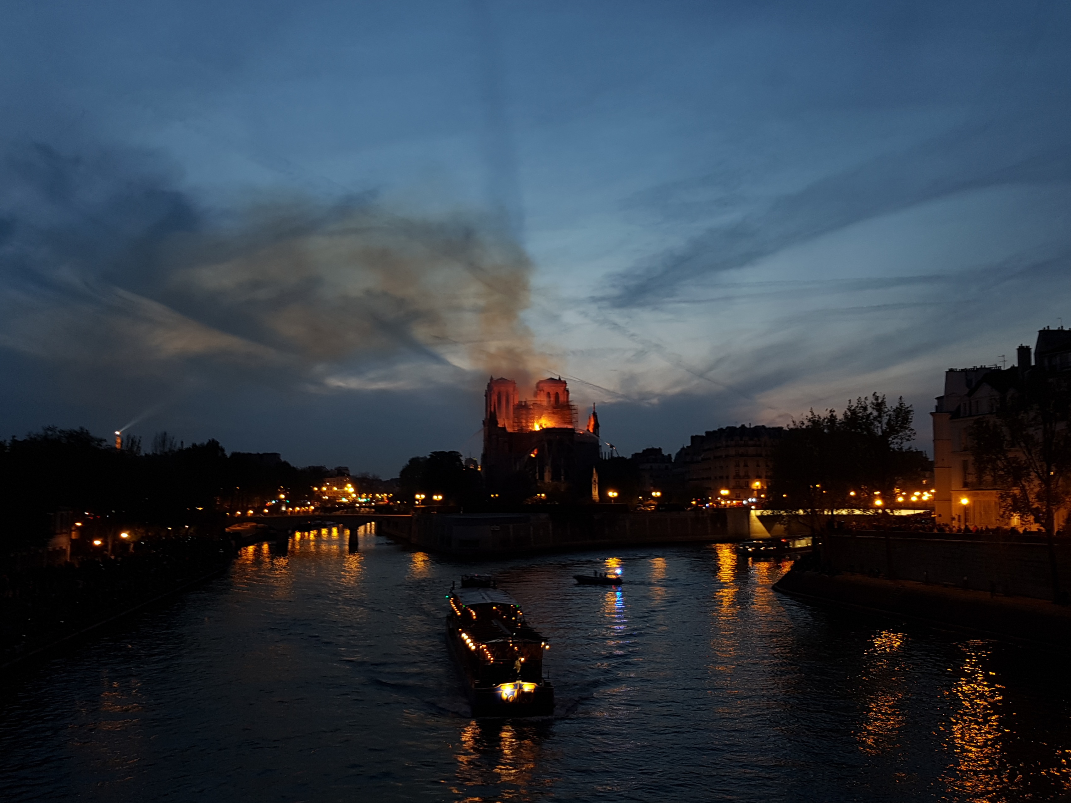 Notre-Dame și fumul de deasupra ei, văzute de dincolo de Sena.
