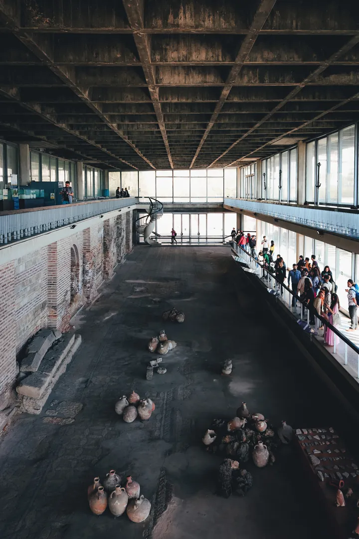 Interiorul edificiului roman cu mozaic: coloane de piatră și podea cu motive geometrice