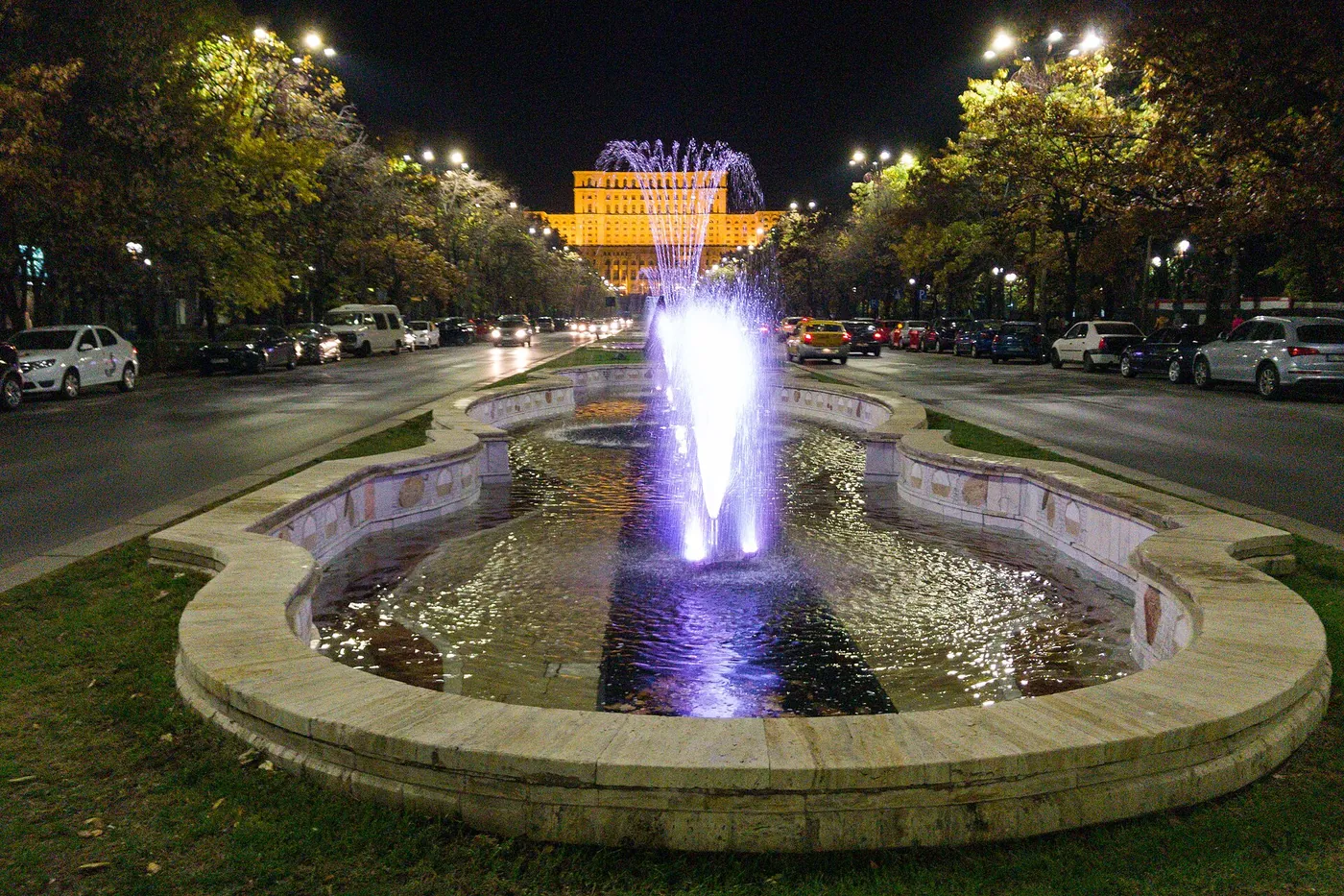 Palatul luminat noaptea, cu fântâna arteziană din față.