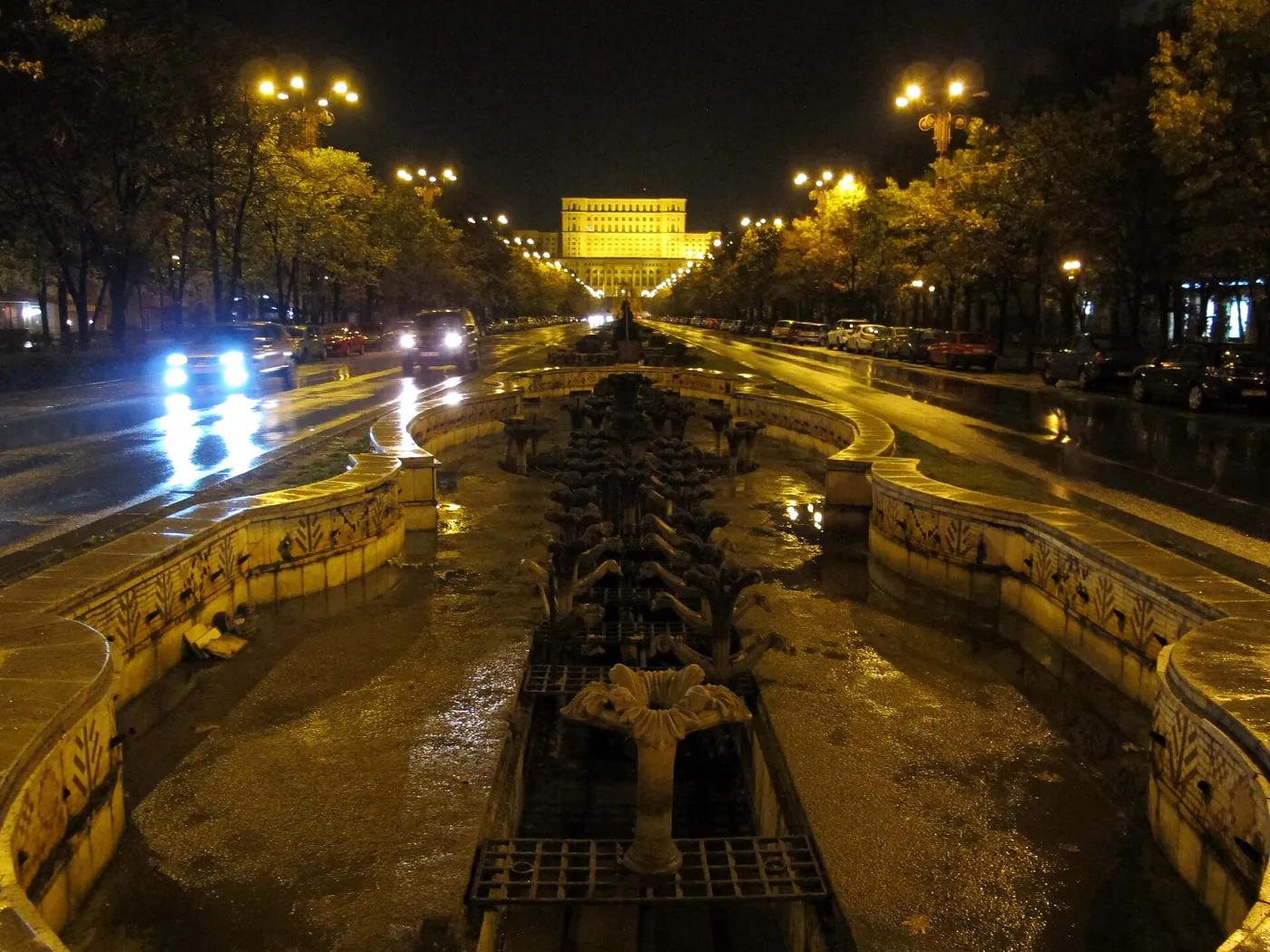 Palatul noaptea, luminat, văzut de pe bulevardul ud.