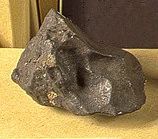 A 69.9 gram Mociu stone: a lumpy blackish-grey rock with hollows, on a light background.