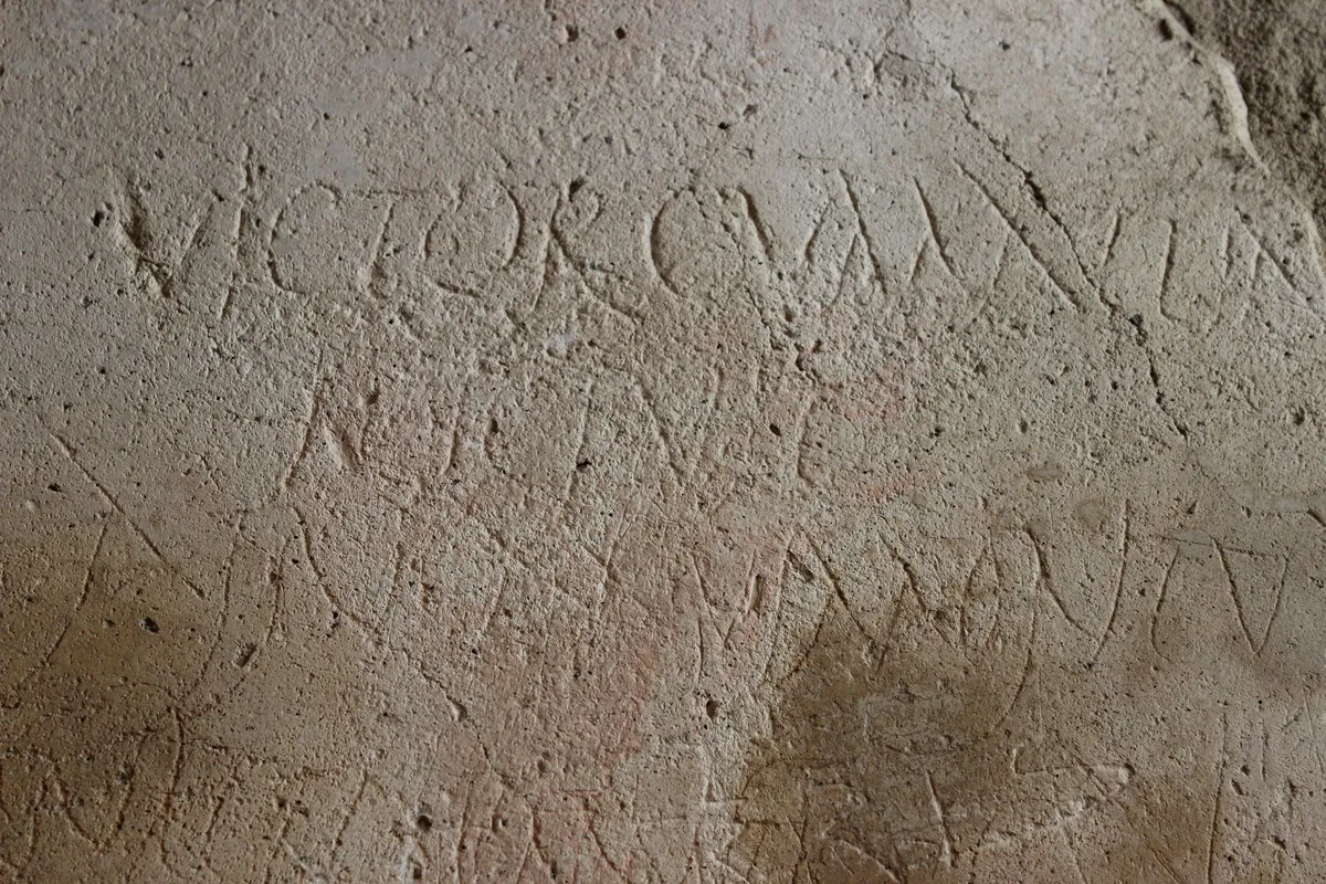 What a graffito in the same building looks like: CIL IV 2258, Victor cum Attine hic fuit, “Victor was here with Attine”, scratched into the pale plaster.
