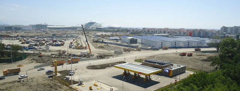 A wide building site with cranes and arenas under construction