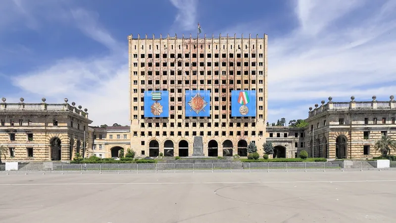 A tall burnt-out building with empty windows behind an empty square
