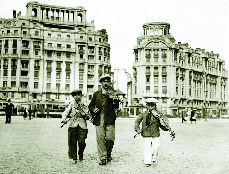 Copii lăutari cu viori pe o stradă din centrul Bucureștiului în anii 1930