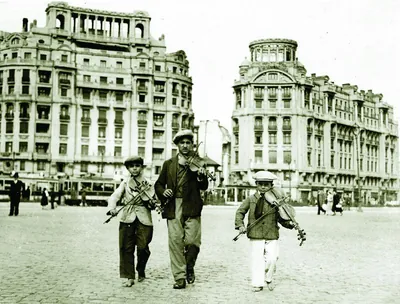 Copii lăutari cu viori pe o stradă din centrul Bucureștiului în anii 1930