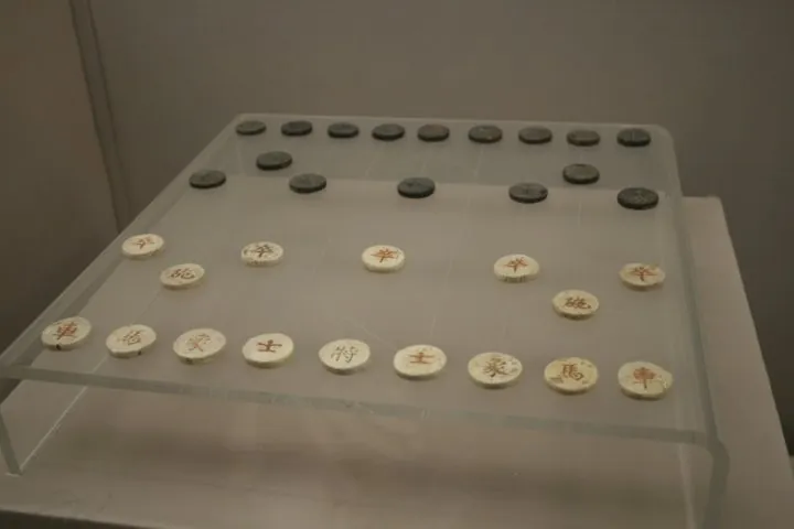 博物馆展柜里,写着汉字的圆形棋子摆在透明的托架上。
